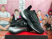 Angled view of the pair highlighting the black upper, silver gradient sole, and Under Armour branding.