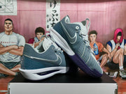 Angled side view showing perforated gray panels, white Nike Swoosh details, purple outsole sections, and ZoomX wording.