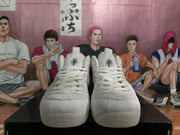Front view of a pair of white high-top basketball sneakers with lace-up closures and padded tongues.