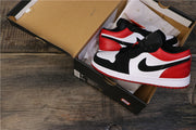 Black, white, and red Air Jordan 1 Low sneakers displayed in an open shoebox.
