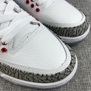 Close-up of the sneaker's white upper, laces, red eyelets, and elephant-print toe overlay