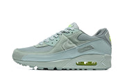 Side profile of gray Nike Air Max 90 QS sneakers with lime accents and a visible Air unit.