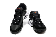 Front three-quarter view of black Nike lace-up sneakers with white Swoosh panels and orange tongue details.