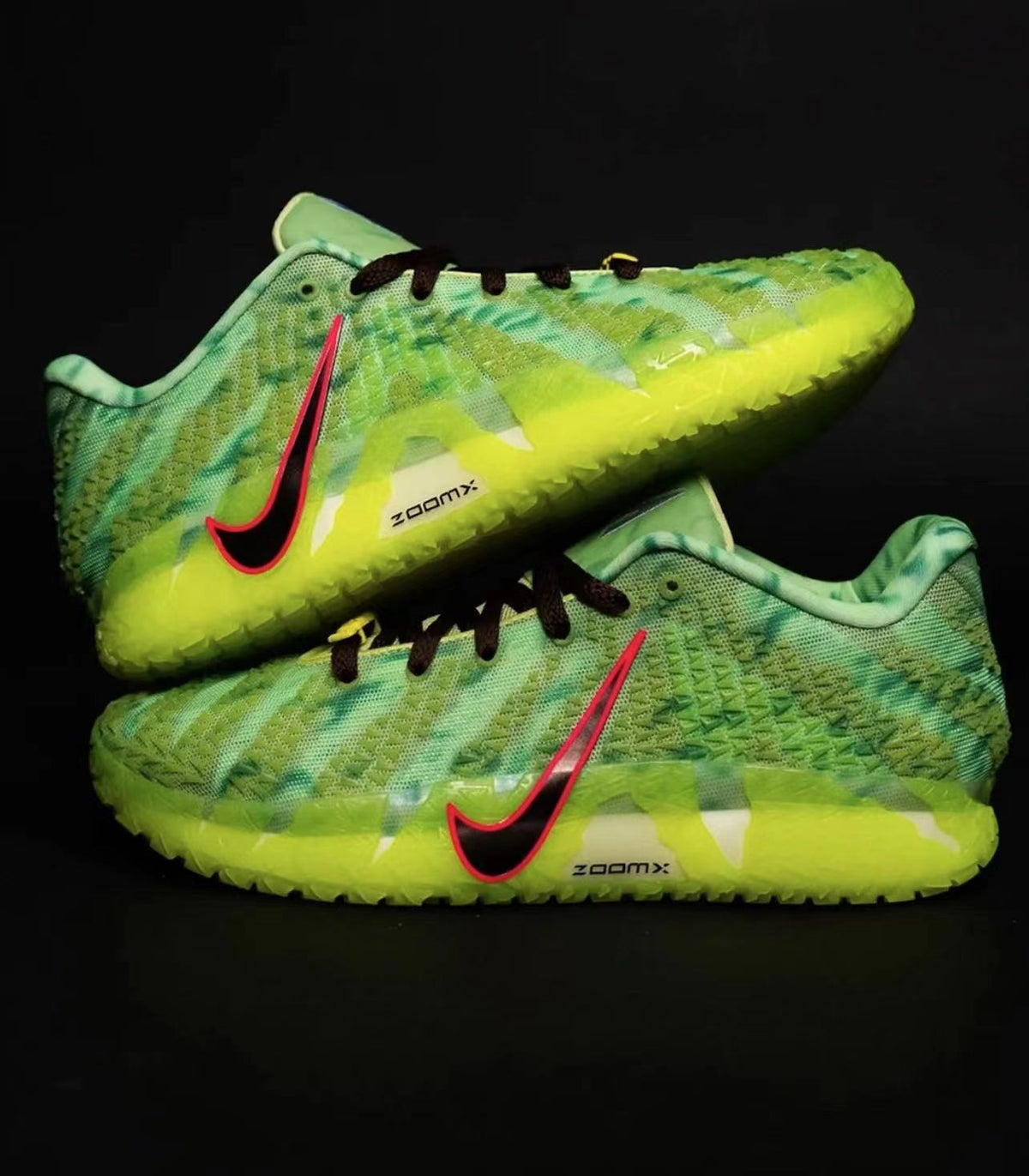 Pair of green Nike sneakers with patterned uppers, dark laces, pink-outlined Swooshes, and bright yellow-green soles.