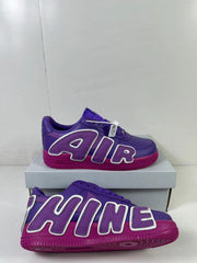 Angled side view of the purple sneakers with contrasting magenta soles and oversized lettering.
