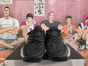 Front view of black lace-up basketball sneakers with subtle red detailing and pale green accents.