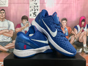 Angled view of blue Nike Kobe basketball shoes with white Swooshes and red heel accents.