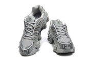 Front view of a pair of grey Nike Shox TL sneakers with lace-up closures and mesh toe areas.