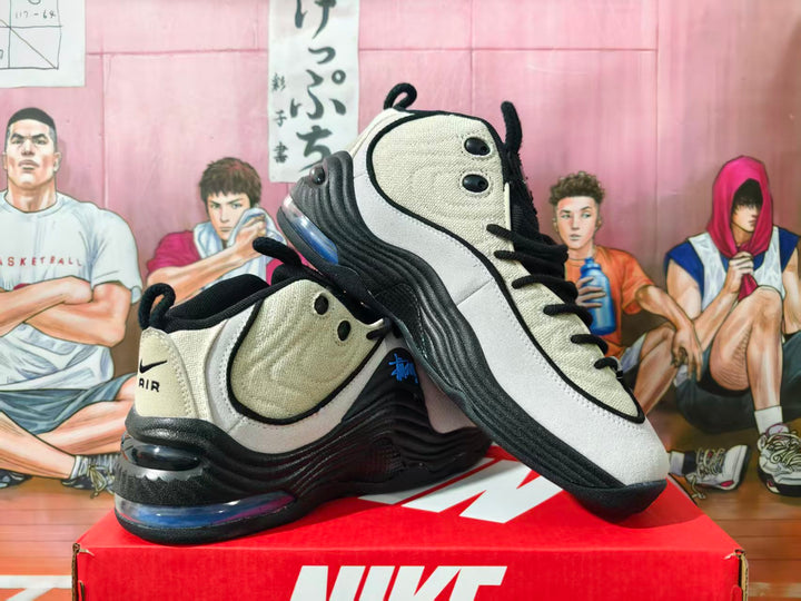 Pair of beige, gray, and black Nike Air Penny 2 style sneakers displayed on a red box
