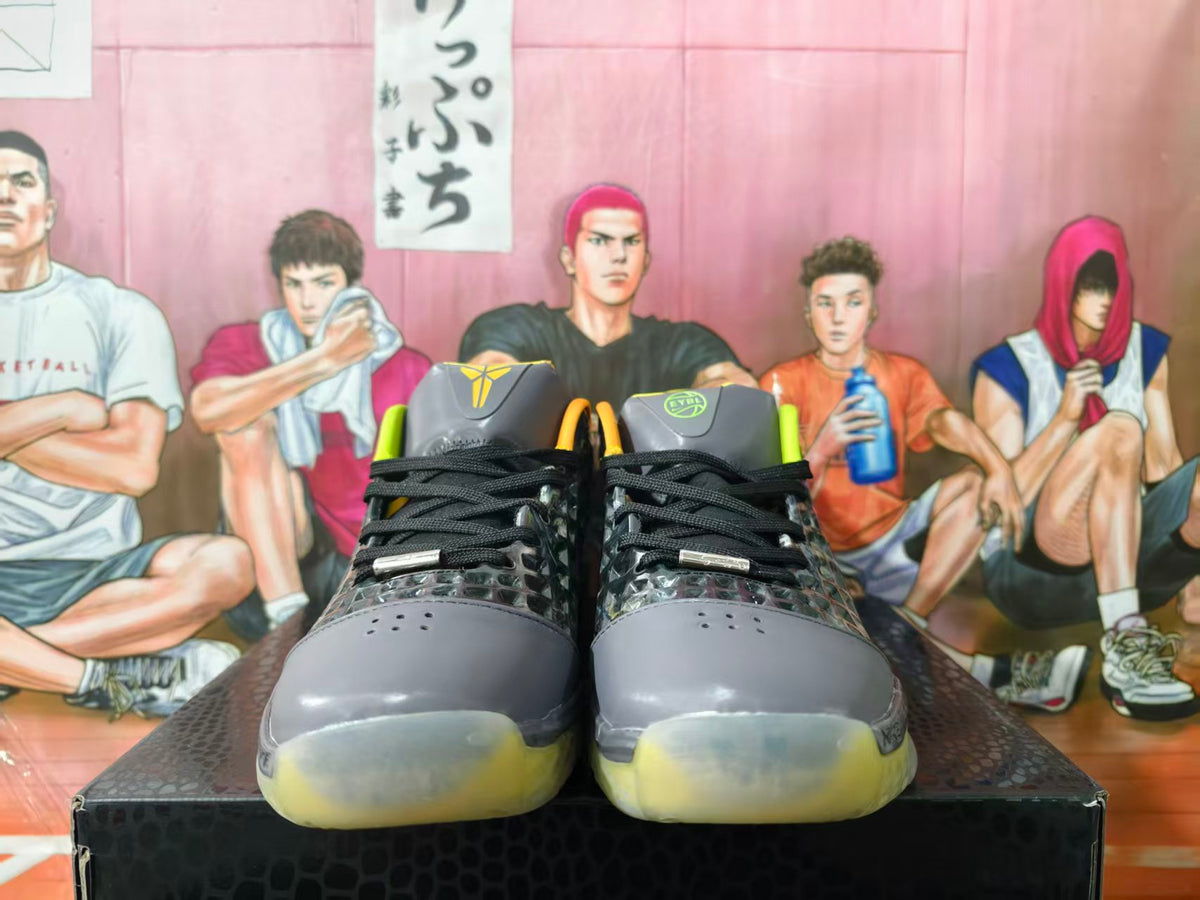 Front view of black and gray Nike basketball sneakers with yellow accents, Kobe logos, and translucent yellow outsoles.