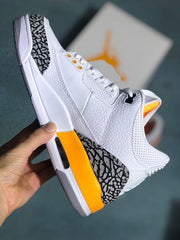 Side profile of the white sneaker with elephant-print panels and orange heel accent.