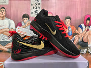 Angled view of two black Nike sneakers with red laces, gold side accents, red outsoles, and contrasting red graphics.