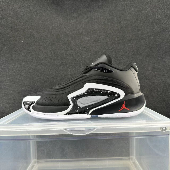 Side view of a black and white Jordan basketball sneaker with a red heel logo and contrasting sole details.