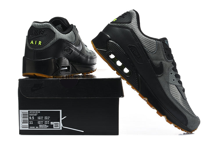 Black and grey Nike Air Max 90 sneakers with gum-colored outsoles displayed with a shoe box