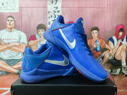 Angled view of blue Nike basketball sneakers showing the white Swoosh, laces, and red accent stitching.