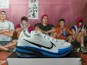 Side view of a white Nike GT basketball shoe with a black Swoosh, blue outsole, and yellow details.