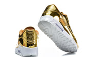 Heel and outsole views of gold-tone Nike Air Max 90 QS sneakers.