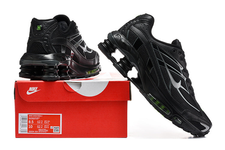 Black Nike Shox Ride 2 sneakers shown from multiple angles on a red box; the box label displays sample size markings.
