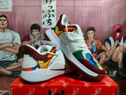 Angled side view showing the white Nike Ja 1 shoe, burgundy collar, multicolor patterned panels, and white midsole.