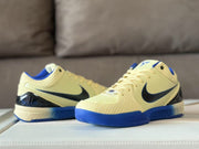 Pair of sneakers shown from front and side angles, highlighting the pale yellow uppers, black Swooshes and blue soles.