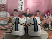 Rear view of white sneakers with dark blue heel stripes and contrasting outsole edges.