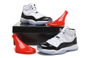 Pair of white and black high-top sneakers displayed beside a black shoe box and red display props.
