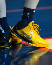 On-foot view of a yellow and black Kobe 5 basketball shoe on a court.