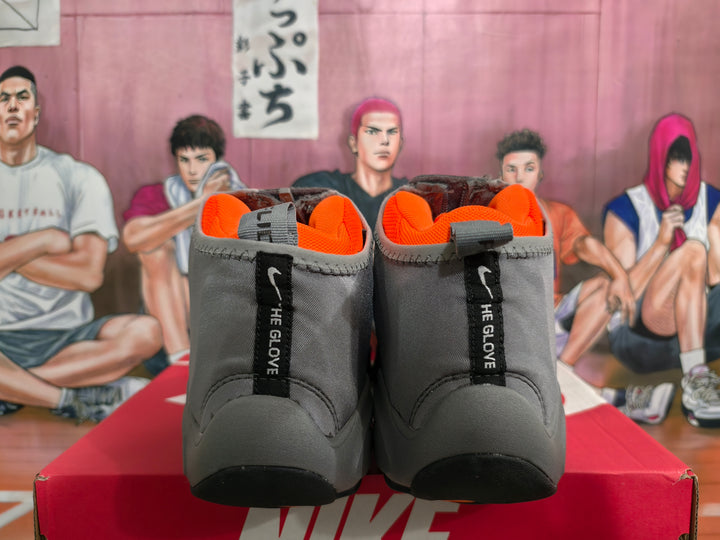 Rear view of gray high-top sneakers with bright orange lining, black heel details, and vertical branding tabs.