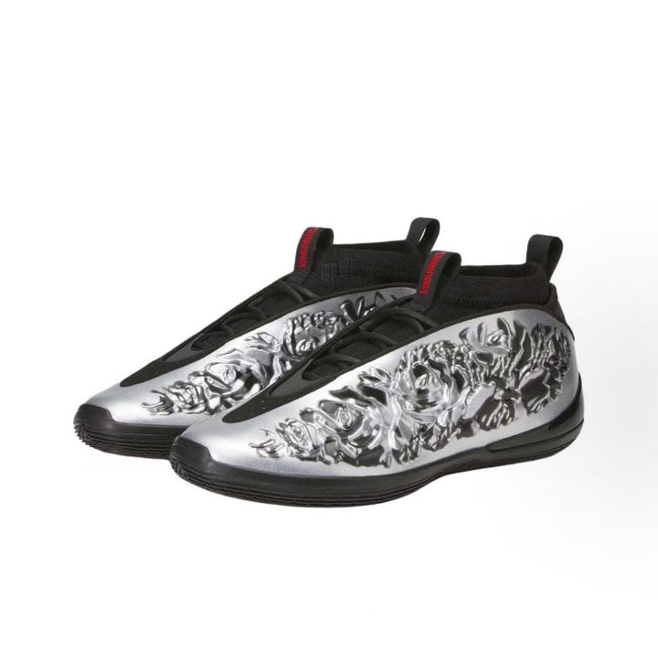 Pair of silver and black slip-on sneakers with textured silver uppers, black detailing, pull tabs, and black rubber outsoles.