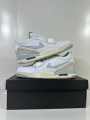 Two Jordan Legacy 312 Low sneakers displayed on a black shoe box, showing the side profile and layered construction.