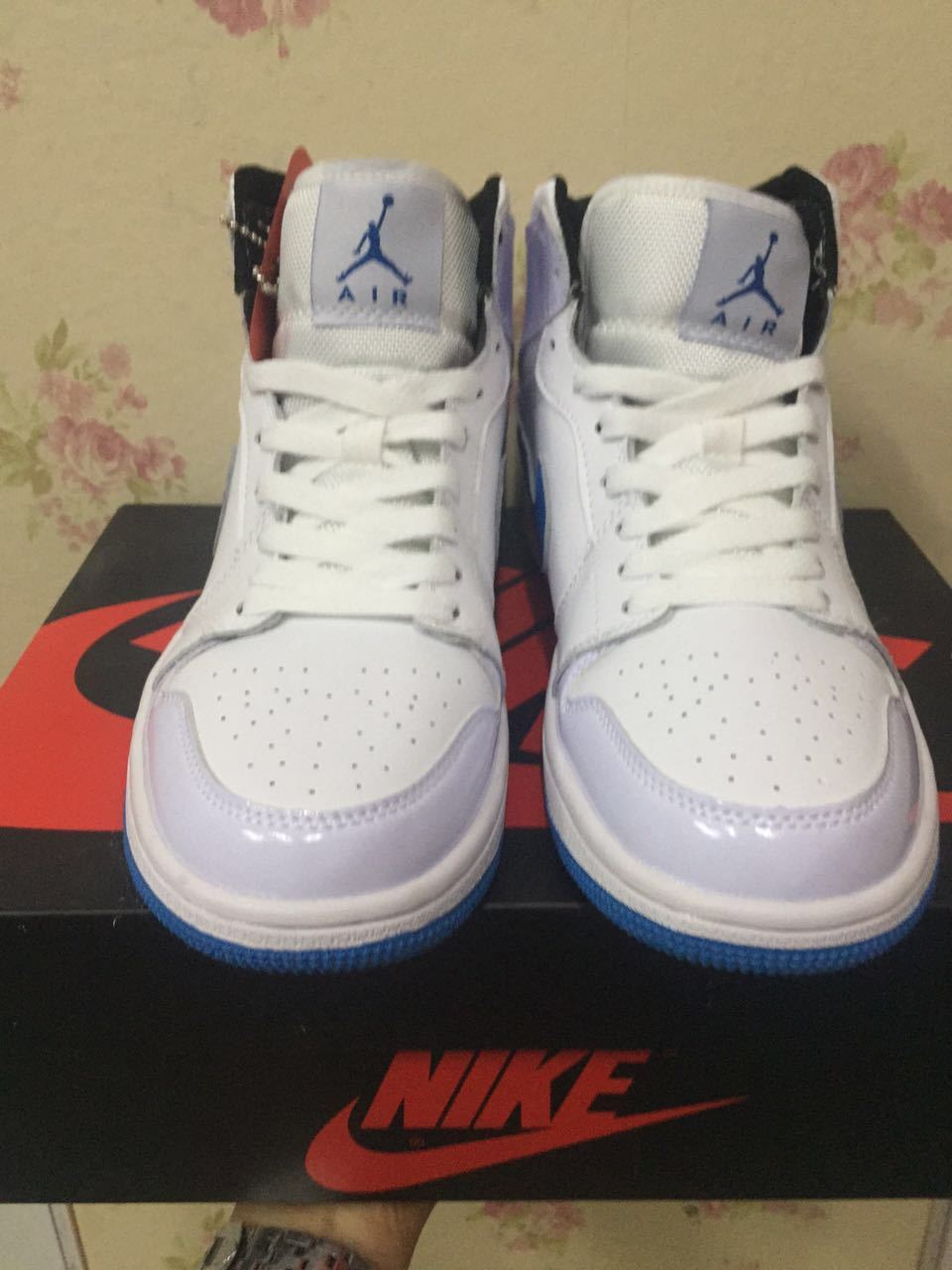 Front view of white and blue high-top sneakers displayed on a branded shoebox.