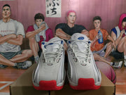 Front view of white Nike sneakers with blue tongue details, white laces, red toe sections, and patterned side panels.