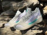 Three-quarter view of the sneakers displayed on rocks, showing the lavender patterned panels.