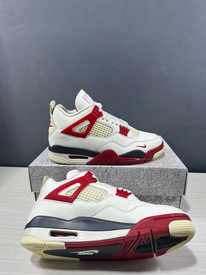 Air Jordan 4 Retro sneakers shown from the side in white with red and dark navy accents, displayed on a shoe box.