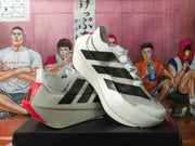 White running shoes displayed at an angle, showing black dotted stripes, red heel accents, and sculpted soles.