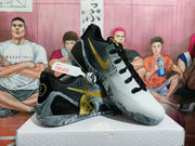 Angled view of the sneakers showing perforated side panels, gold swoosh-style details, black overlays, and marbled soles.