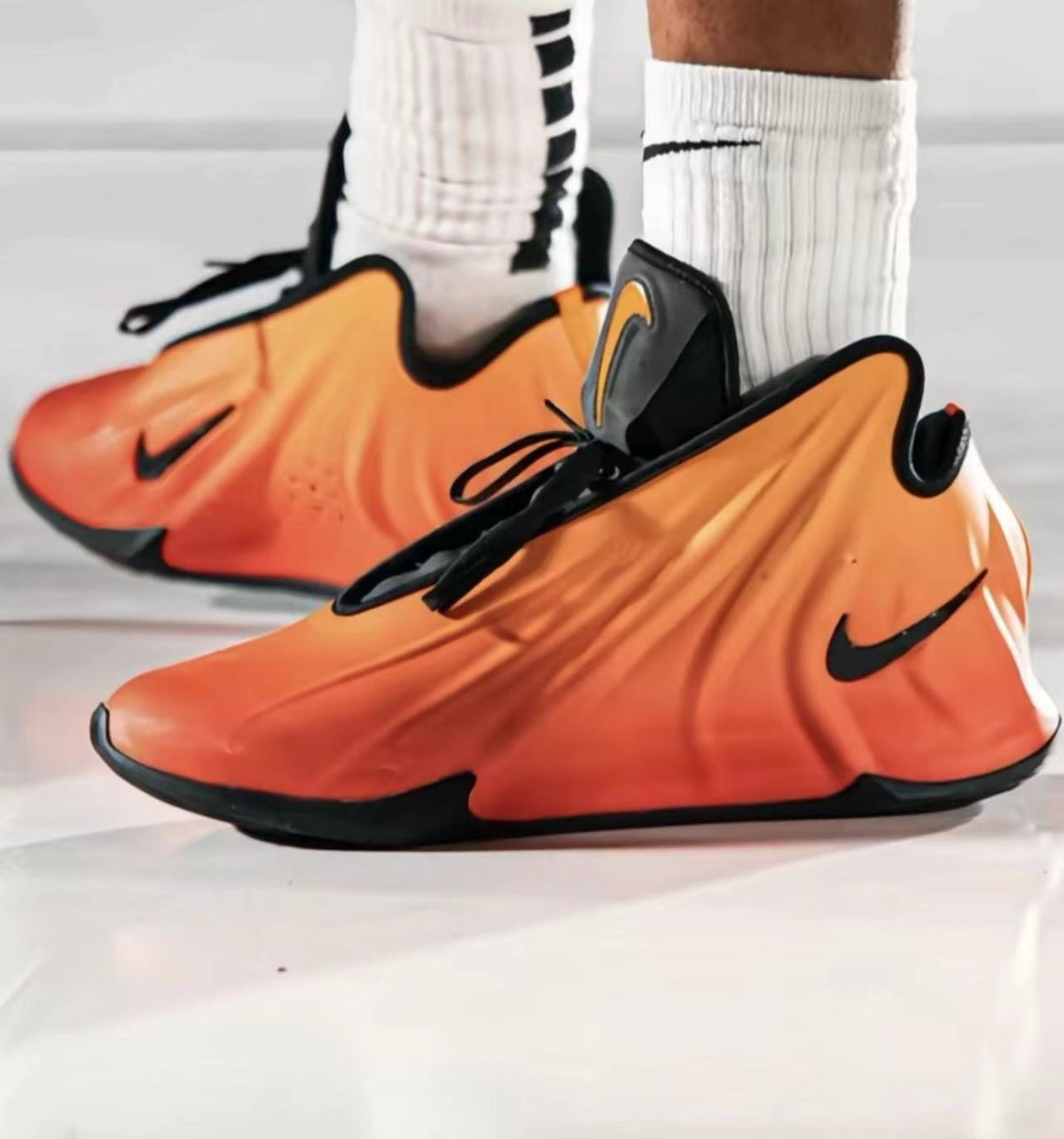 Pair of orange Nike sneakers with black Swoosh logos, black laces, padded collars and black outsoles.