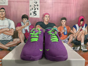 Front view of purple Nike basketball sneakers showing perforated toe boxes, bright green laces, and small green swooshes.