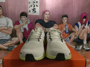 Front view of gray Nike sneakers with black accents and light yellow-green soles on an orange box.