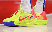 Neon yellow Nike GT 3.5 basketball shoes with blue and coral accents, shown on court.