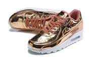 Angled view of rose-gold-toned Nike Air Max 90 QS sneakers with dusty-rose laces.
