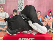 Angled view of paired black and white Nike sneakers showing the side Swoosh details, covered uppers, and contrasting soles.