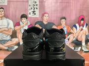 Rear view of black sneakers showing textured collars, glossy heel panels, and gold-colored heel detailing.