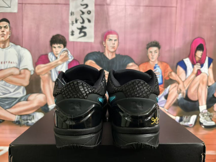 Rear view of black sneakers showing textured collars, glossy heel panels, and gold-colored heel detailing.