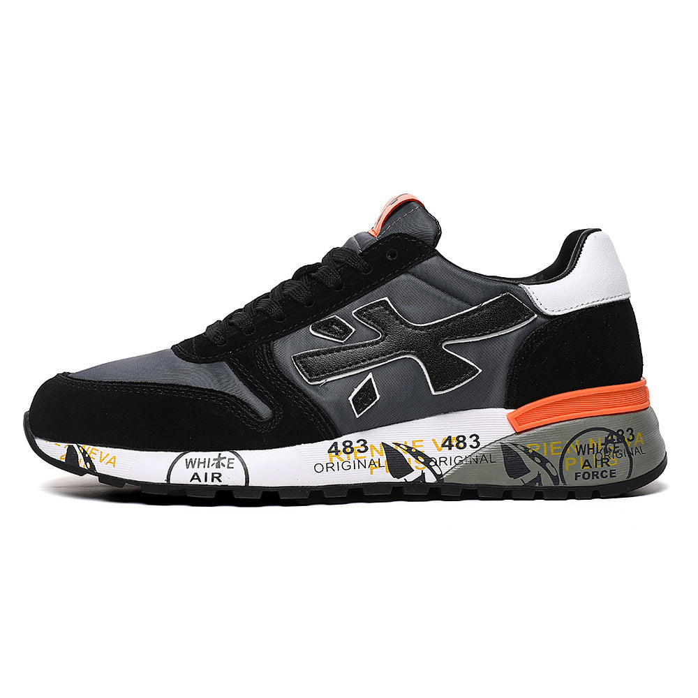 Side view of black and gray Premiata low-top sneakers with white heel panel, orange accents, and printed midsole graphics