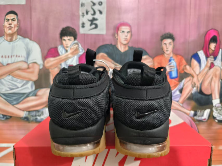 Rear view of black Nike sneakers showing pull tabs, padded collars, visible cushioning units, and gum-colored outsoles on a red shoebox.