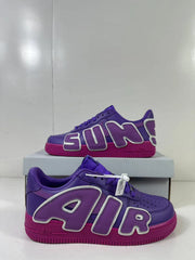 Close angled view of the purple sneakers, oversized AIR lettering and magenta soles.
