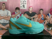 Side view of a teal Nike basketball sneaker showing gold side branding, textured upper, and Nike Zoom midsole marking.