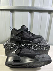Two black Jordan Spizike Low sneakers shown from side and outsole angles, highlighting the layered panels, textured accents, and tread pattern.