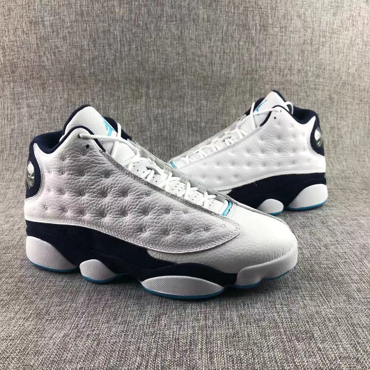 Pair of white, navy, and blue Jordan high-top sneakers shown from a front three-quarter angle.
